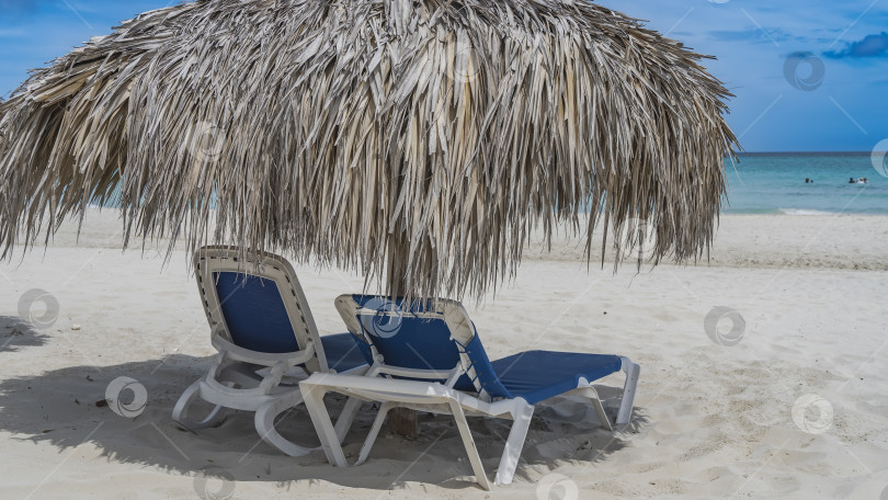 Скачать Два шезлонга на песчаном пляже под соломенным зонтом. фотосток Ozero