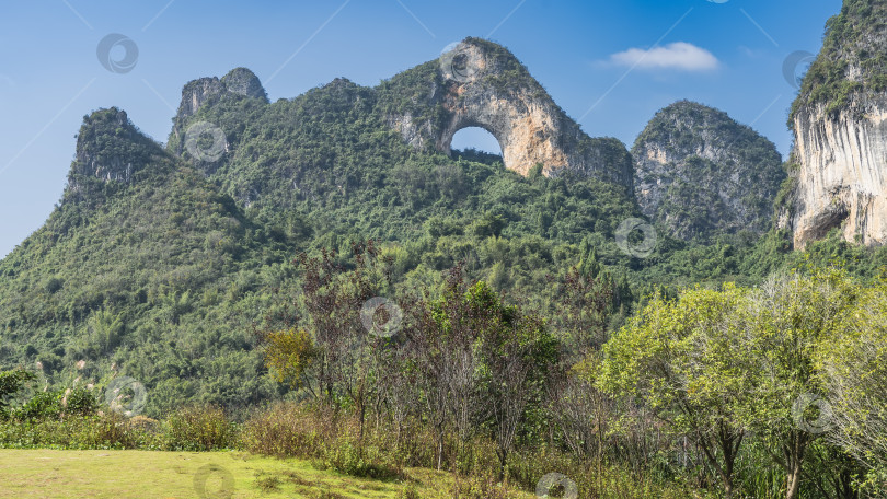Скачать Живописные горы. На вершине скалы находится естественная округлая каменная арка. фотосток Ozero