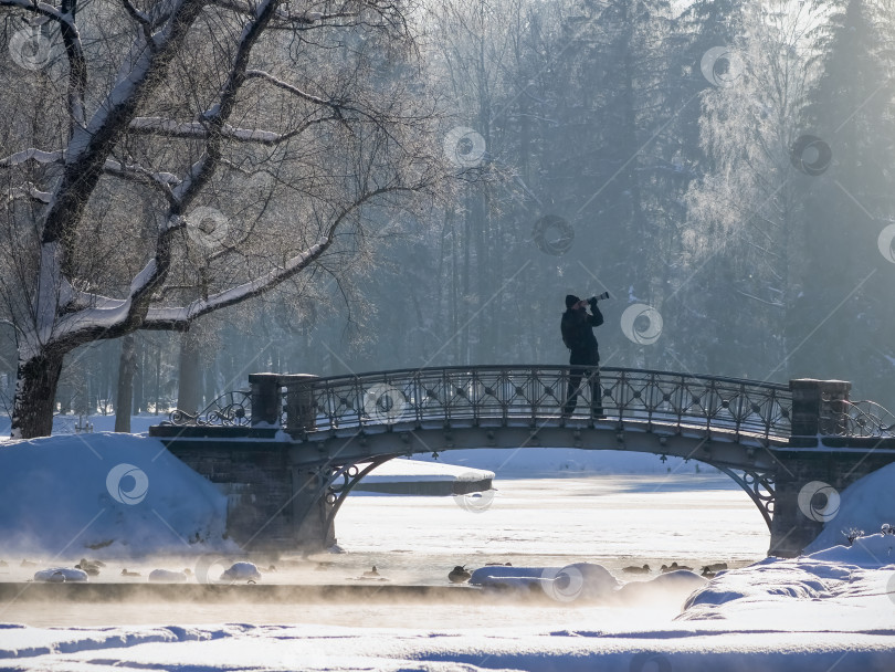 Скачать Мужчина фотографирует мост через замерзшую реку фотосток Ozero