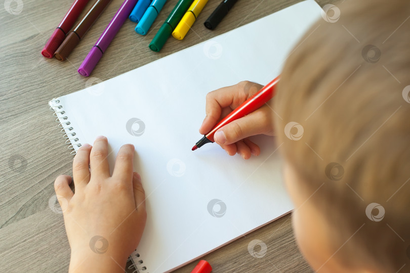 Скачать Маленький ребенок рисует дом фломастерами в альбоме. Пошаговые инструкции фотосток Ozero