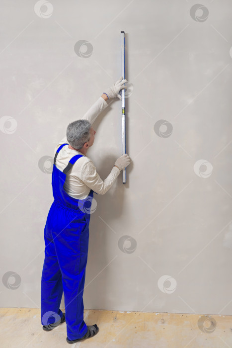 Скачать Измерительный уровень в руках сотрудника-мужчины. фотосток Ozero