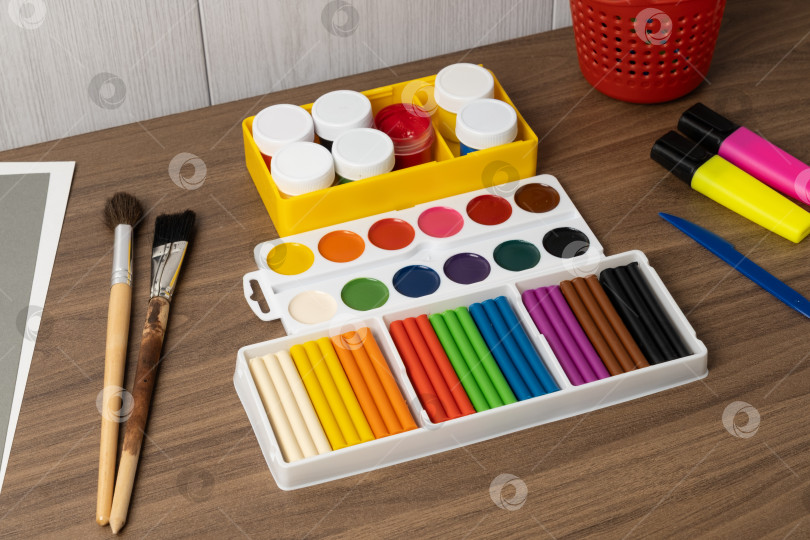 Скачать На столе разложены принадлежности для рукоделия, краски, фломастеры и кисти, готовые к творческим проектам в рабочей обстановке фотосток Ozero