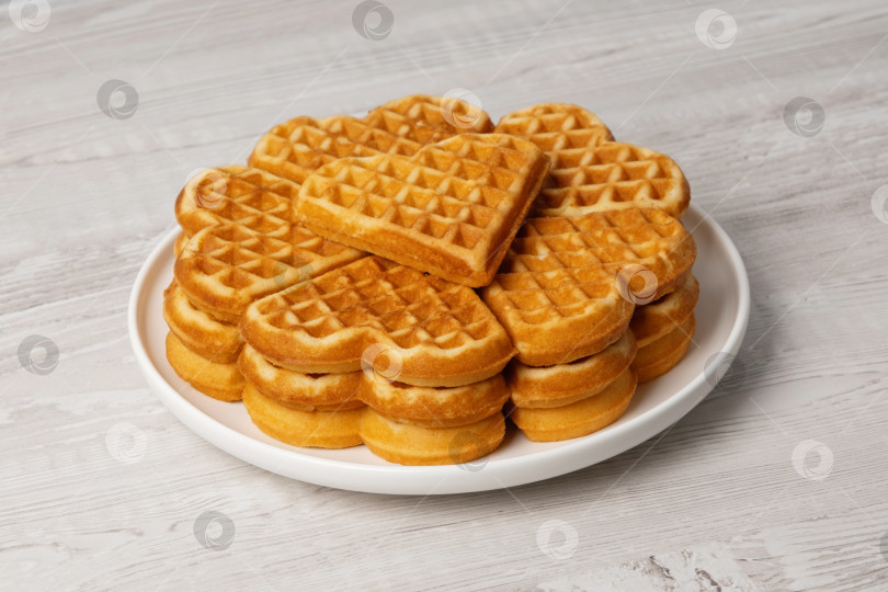 Скачать Свежеприготовленные вафли подаются на круглой белой тарелке аккуратной стопкой, одна из которых лежит сверху, на завтрак фотосток Ozero
