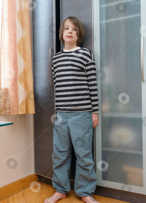 Скачать Вертикальный портрет босоногого мальчика в полный рост, стоящего у гардероба. Повседневная детская мода фотосток Ozero