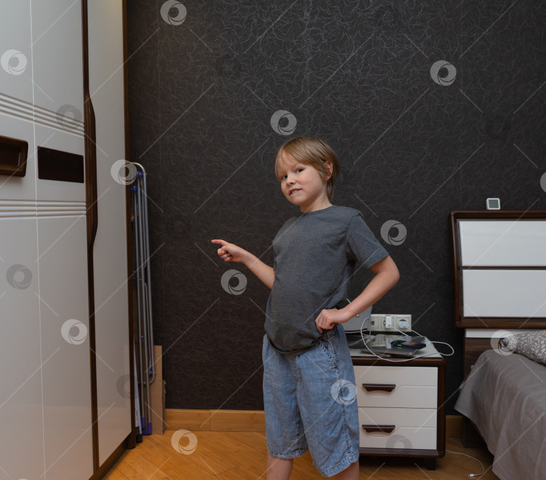 Скачать Маленький мальчик указывает пальцем в сторону в спальне. Ребенок указывает на место для копирования фотосток Ozero