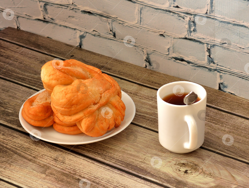 Скачать Чашка черного чая и тарелка с двумя сахарными крендельками на деревянном столе. фотосток Ozero