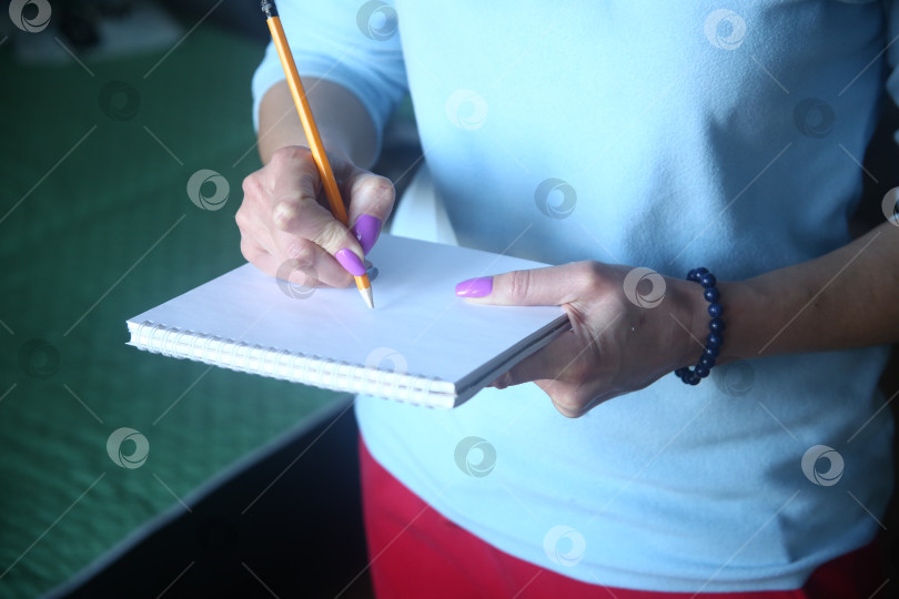 Скачать Женщина пишет карандашом в блокноте фотосток Ozero