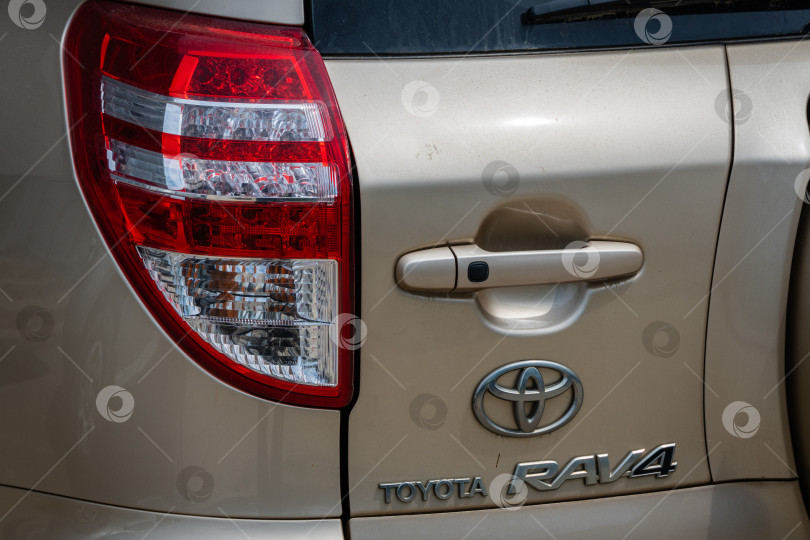 Скачать Левый задний фонарь автомобиля Toyota RAV4. Логотип Toyota под ручкой багажника. Крупный план. Автомобиль на стоянке в Архипо-Осиповке. фотосток Ozero