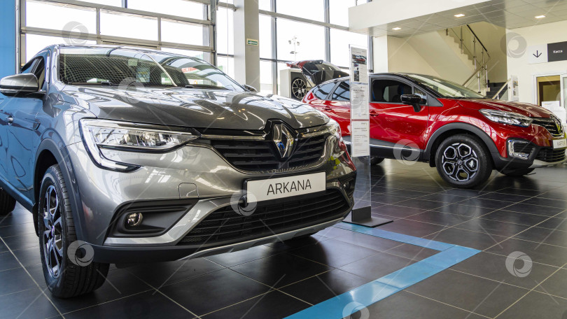 Скачать Серый внедорожник Renault Arkana в автосалоне Renault. На заднем плане - красный внедорожник Kaptur. Автомобиль крупным планом. Автосалон Renault в Мега Адыгея. фотосток Ozero
