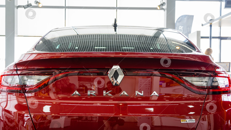 Скачать Красный внедорожник Renault Arkana в автосалоне. Крупный план задней части автомобиля с задними фонарями, дверью багажника с надписью Arkana и логотипом Renault. Автосалон Renault в Мега Адыгея. фотосток Ozero