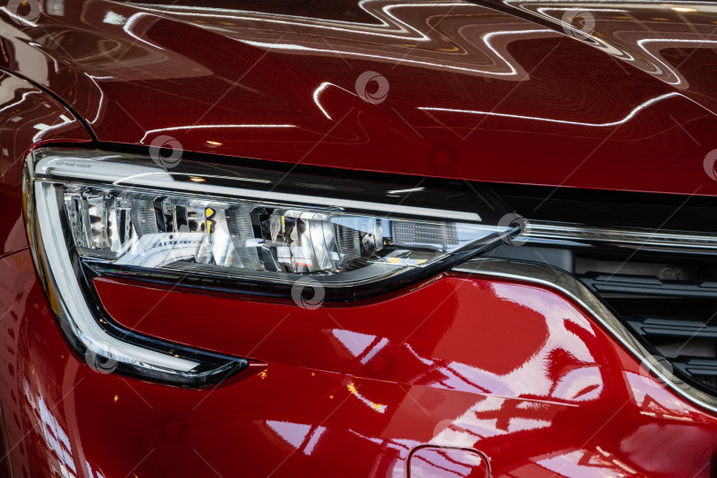 Скачать Красный внедорожник Renault Arkana в автосалоне. Крупный план передней правой фары. Автосалон Renault в Мега Адыгея. фотосток Ozero