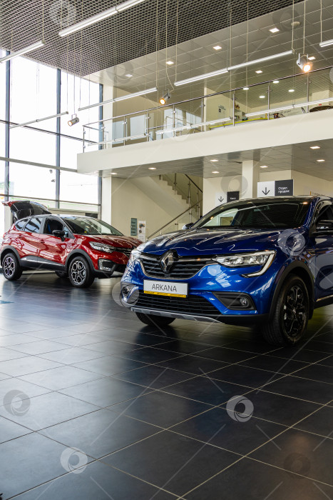 Скачать Синий внедорожник Renault Arkana в автосалоне. Крупный план. На заднем плане красный внедорожник Renault Captur. Автосалон Renault в Мега Адыгея. фотосток Ozero