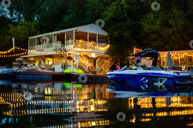 Скачать Москва, Россия - 11.06.2025: [Пристань с катерами и фонарями вечером  на реке Сходня Июнь 2025 ] фотосток Ozero