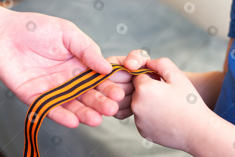Скачать оранжево-черная полосатая лента - символ 9 мая в руках, выделенный на белом фоне. день победы фотосток Ozero