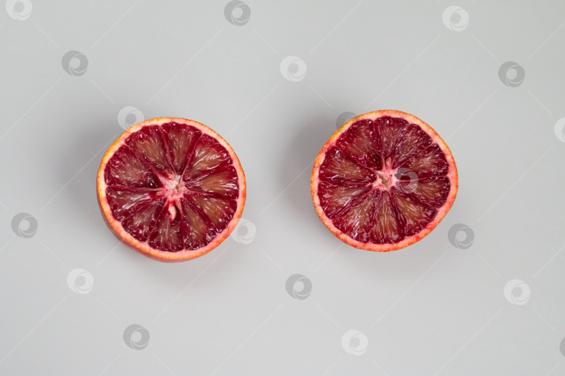 Скачать ломтик красного апельсина на сером фоне фотосток Ozero