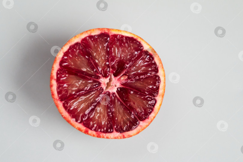 Скачать ломтик красного апельсина на сером фоне фотосток Ozero