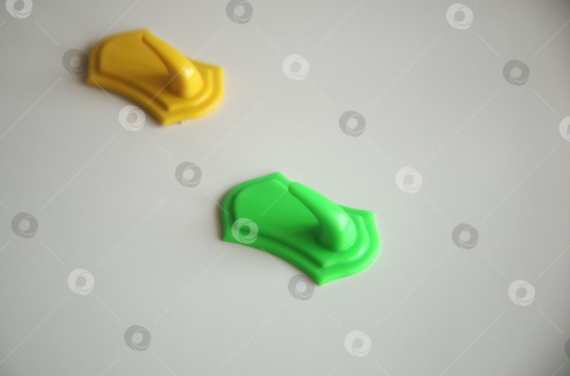 Скачать Жёлтый и зеленый крючки для полотенец на столе. Изолировано фотосток Ozero