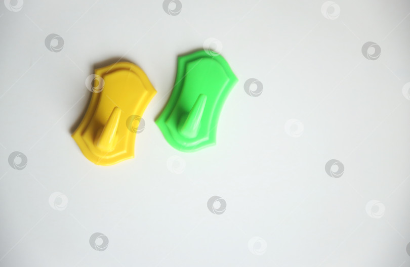 Скачать Жёлтый и зеленый крючки для полотенец на белом. Крупный план. Изолировано фотосток Ozero