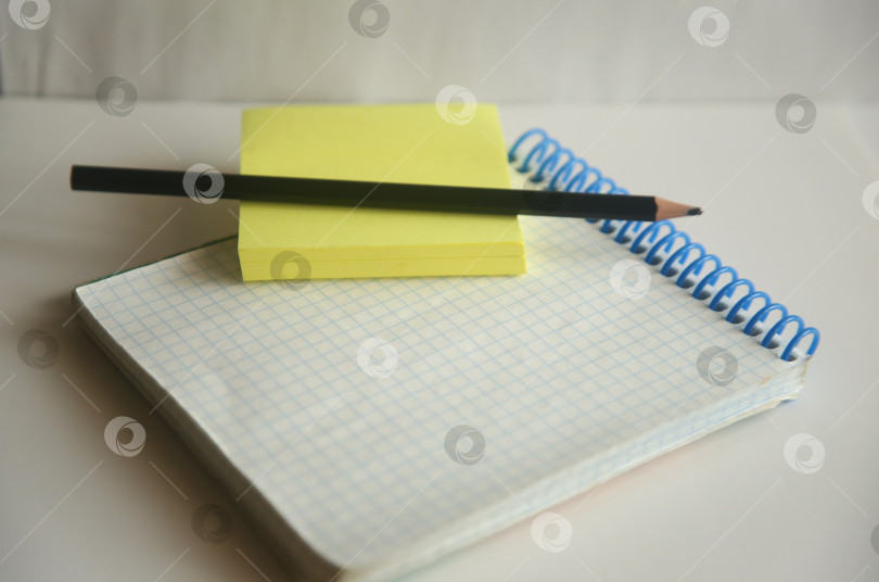 Скачать Блокнот в клетку, стикер и карандаши на столе фотосток Ozero