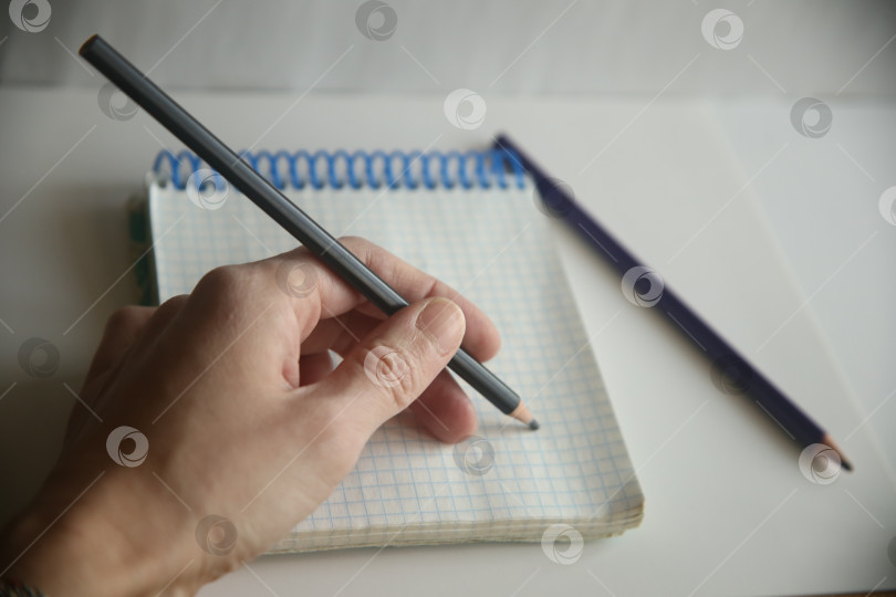 Скачать Женщина пишет левой рукой карандашом в блокноте в клетку крупным планом фотосток Ozero