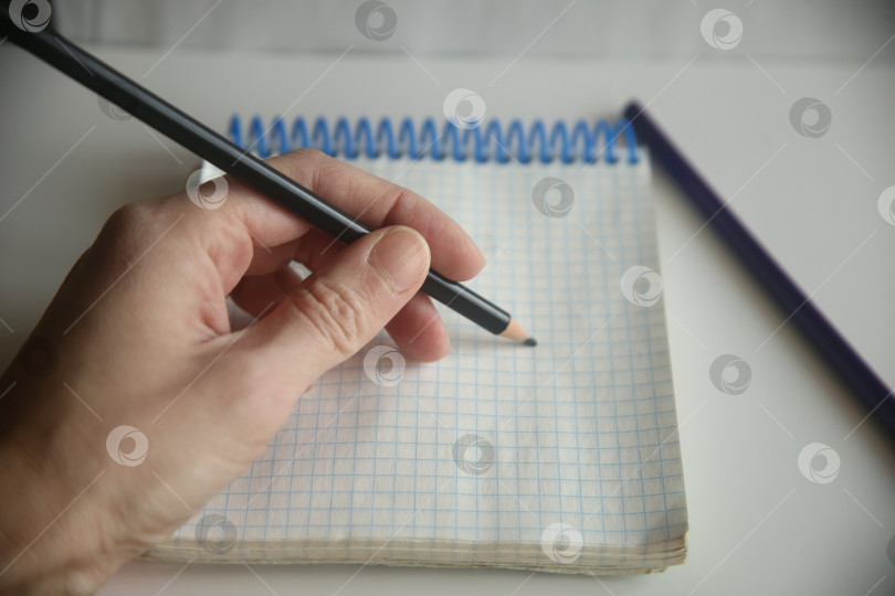 Скачать Женщина пишет карандашом в блокноте левой рукой фотосток Ozero