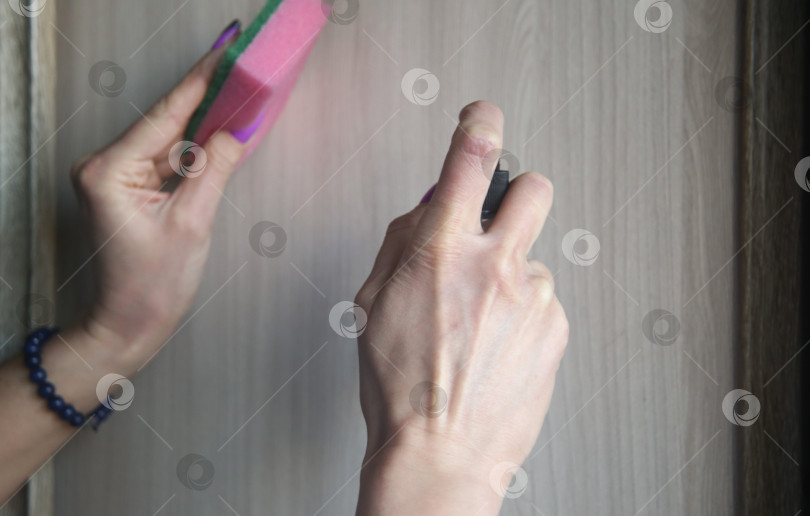 Скачать Женская рука делает уборку с помощью специального средства с распылителем и губкой. Тема уборки фотосток Ozero