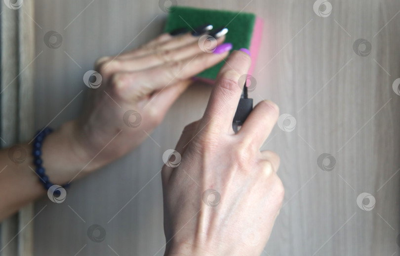 Скачать Женщина протирает пыль с помощью средства для уборки и губки фотосток Ozero