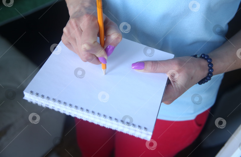 Скачать Женщина пишет карандашом в блокноте красивой рукой с маникюром крупным планом фотосток Ozero