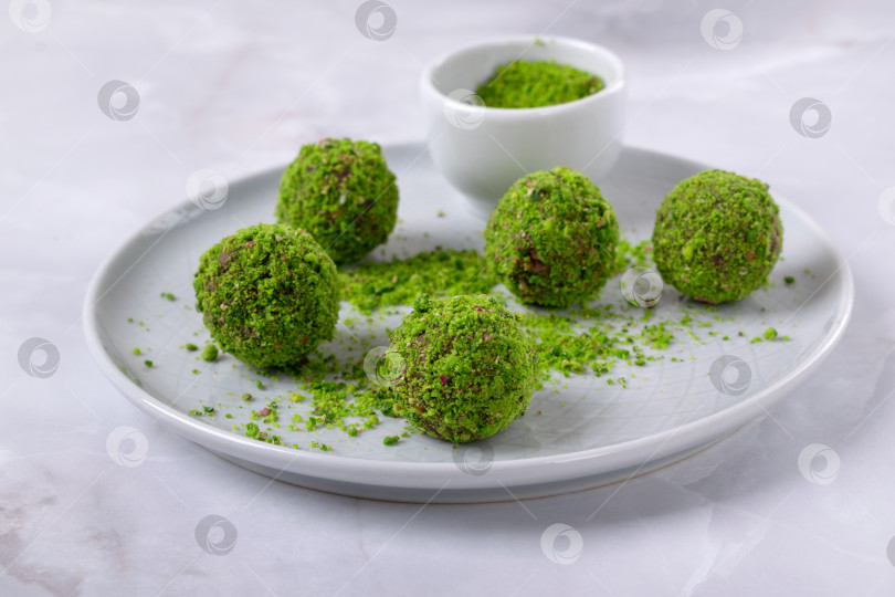 Скачать Шоколадные конфеты с посыпкой из молотых фисташек на керамической тарелке фотосток Ozero