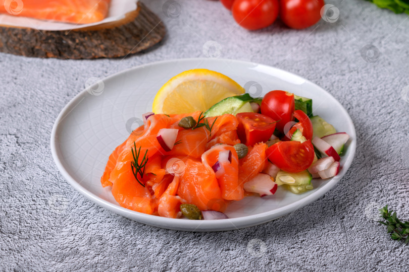 Скачать Салат из соленого филе форели и свежих овощей с ломтиком лимона на керамической тарелке фотосток Ozero