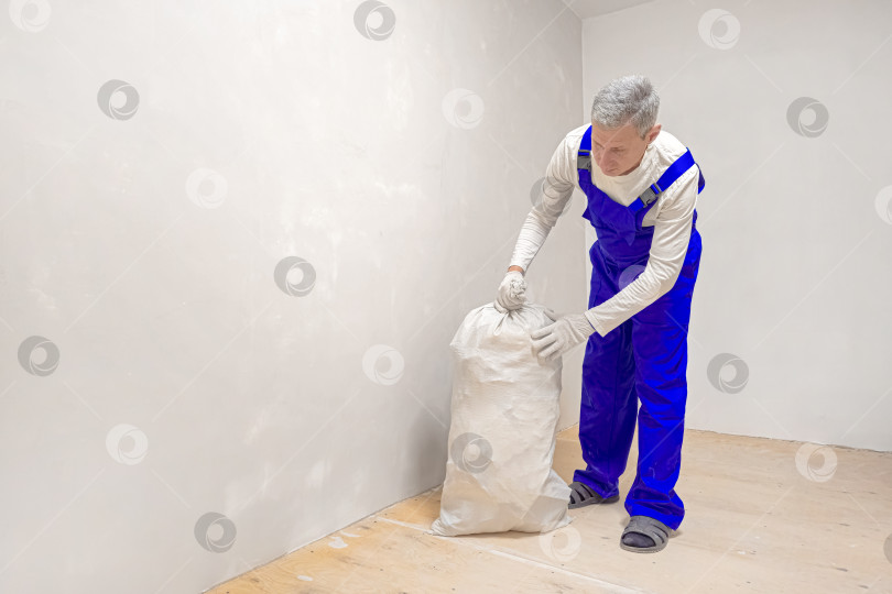 Скачать Мужчина несет строительный мусор в белом пакете. фотосток Ozero