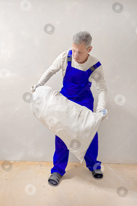 Скачать Вид сверху: мужчина несет строительный мусор в белом мешке. фотосток Ozero