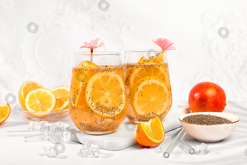 Скачать Современный натюрморт с цитрусовыми. Диетический веганский коктейль с семенами чиа, апельсином, лаймом, фиалкой и льдом. Концепция детокс-диеты и похудения. Летний баннер и шаблон для оформления экрана. фотосток Ozero