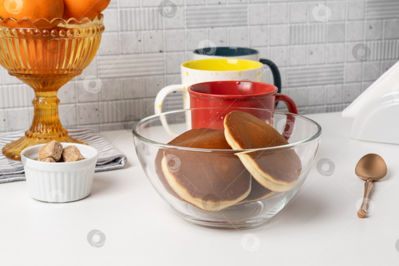 Скачать Сервировка завтрака с блинчиками и кофейными чашками на столе в светлой кухне в утренние часы фотосток Ozero