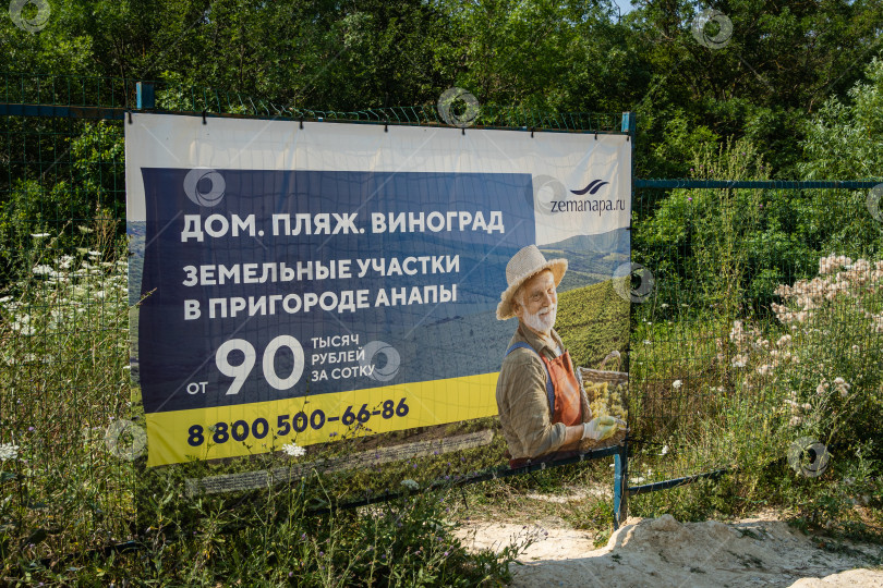 Скачать Баннер с мужчиной, похожим на моего любимого актера Джона Малковича. Надпись: Дом, пляж, виноград, участок в пригороде Анапы от 90 тысяч рублей за сотку.Сукко, Россия - 20 июля 2021 года фотосток Ozero
