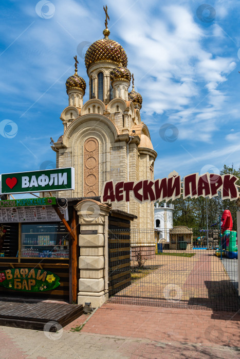 Скачать Парк развлечений в Архипо-Осиповке. Часовня в парке для детей на фоне гор с колесом обозрения и голубого неба. Позолоченные купола и православные кресты. фотосток Ozero