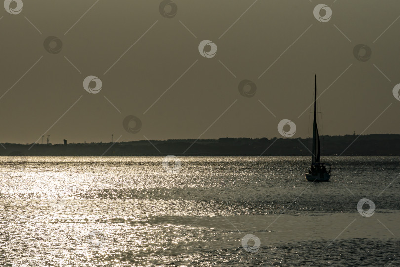 Скачать Корабль на фоне серебристого спокойного Черного моря на закате. Солнечная дорожка на воде делает пейзаж умиротворяющим и волшебным. фотосток Ozero