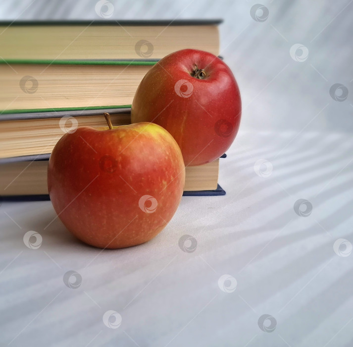 Скачать Большие красные яблоки на фоне стопки книг фотосток Ozero