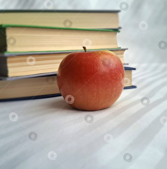 Скачать Большое красное яблоко на фоне стопки книг фотосток Ozero