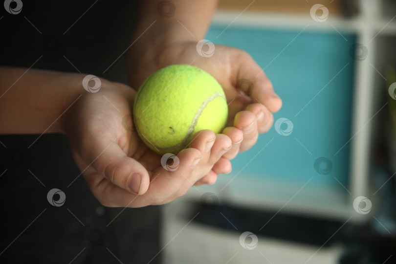 Скачать Мальчик держит маленький зелёный бейсбольный мячик для игр в обеих руках крупным планом фотосток Ozero