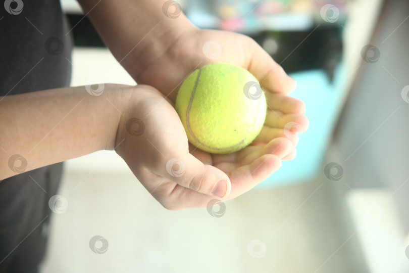 Скачать Ребенок держит бейсбольный салатовый мяч в руках фотосток Ozero
