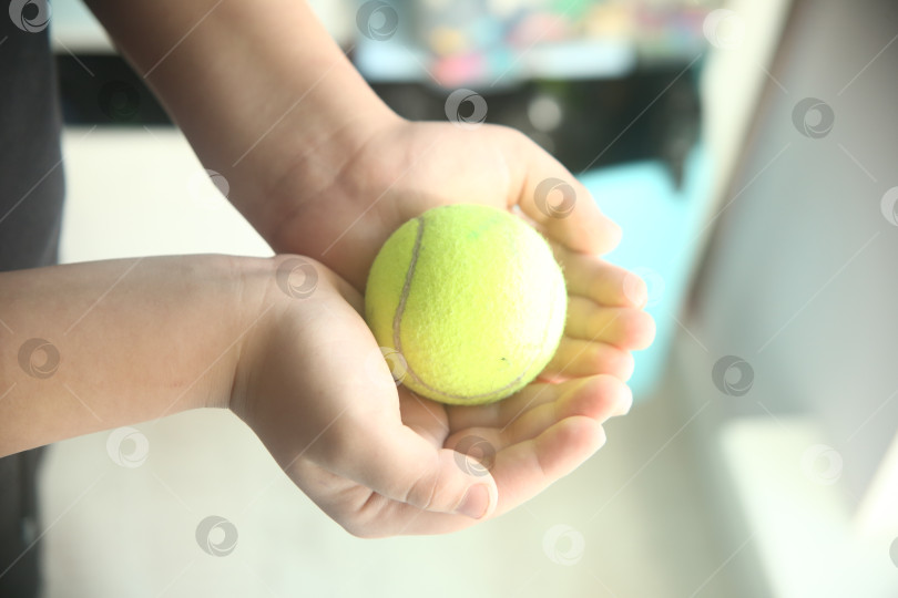 Скачать Ребенок держит бейсбольный салатовый мяч для игр в руках фотосток Ozero