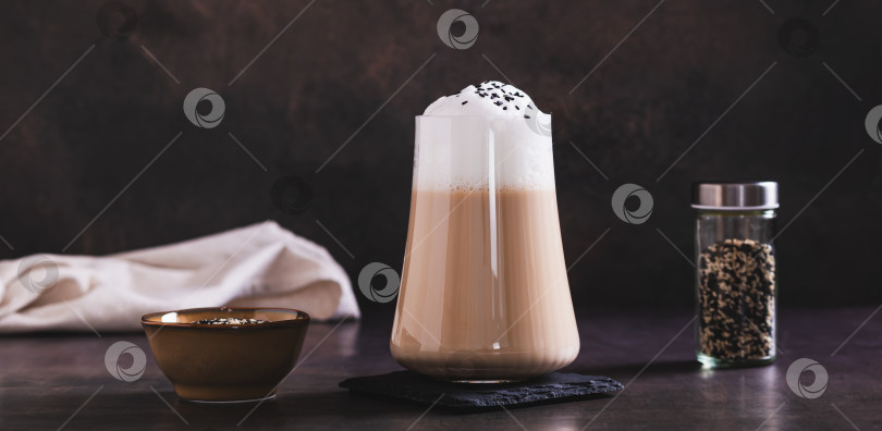 Скачать Изысканный напиток латте с черным кунжутом в бокале на столе - веб-баннер фотосток Ozero