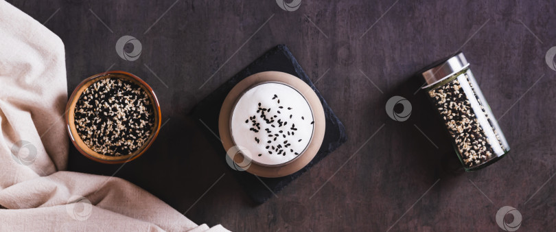 Скачать Черный кунжутный кофе с пышной сливочной пенкой в бокале на столешнице посмотреть веб-баннер фотосток Ozero