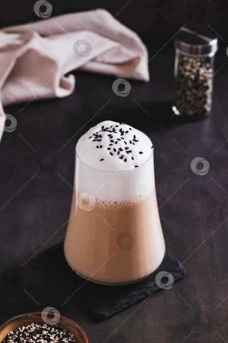 Скачать Черный кунжутный кофе с пышной сливочной пенкой в бокале на столе, вид сверху фотосток Ozero