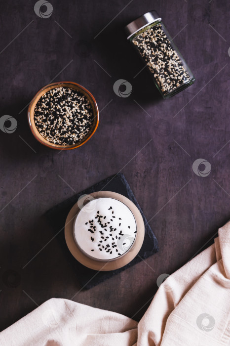 Скачать Черный кунжутный кофе с пышной сливочной пенкой в бокале на столешнице и в вертикальном положении фотосток Ozero