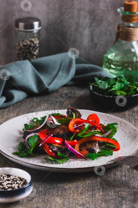 Скачать Теплый салат с жареными баклажанами, болгарским перцем, луком и зеленью на тарелке, поданный на стол в вертикальном положении фотосток Ozero