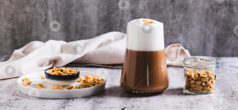 Скачать Изысканный арахисовый кофе раф в бокале на веб-баннере на столе фотосток Ozero