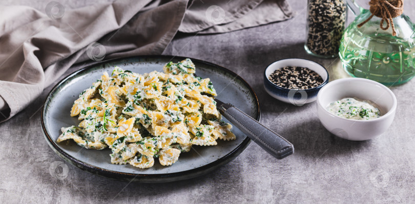 Скачать Аппетитные фарфалле с рикоттой и шпинатом на тарелке на столе - веб-баннер фотосток Ozero