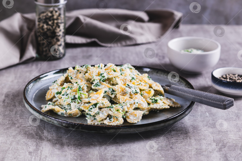 Скачать Аппетитные фарфалле с рикоттой и шпинатом на тарелке подаются на стол фотосток Ozero